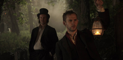 Larry Fessenden and Dominic Monaghan in a dark forest by lamplight